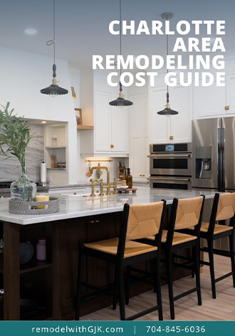 Modern kitchen with white cabinets, pendant lights, stainless steel appliances, and a marble island with chairs. Text reads "Charlotte Area Remodeling Cost Guide.