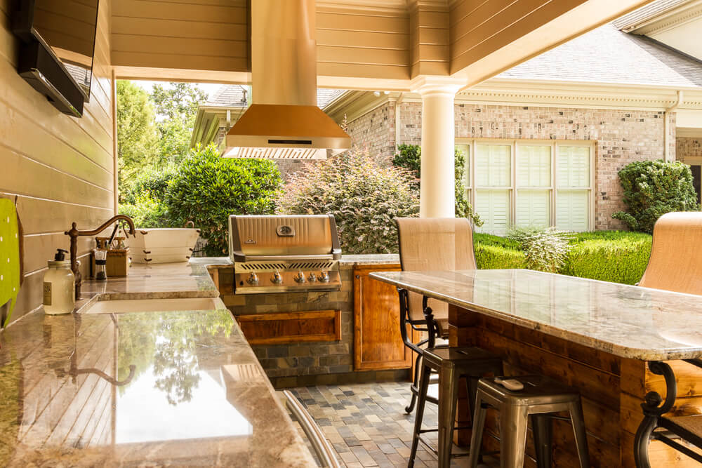 An outdoor kitchen with a grill and bar stools in Charlotte