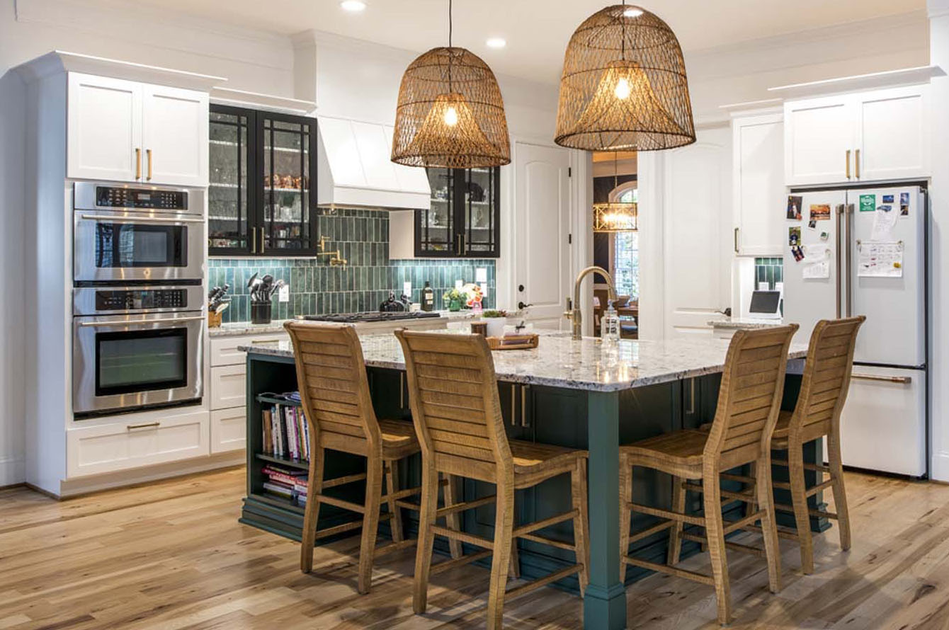 Modern kitchen remodeling with white cabinets, a central island with four stools, built-in appliances, and two hanging woven lamps.