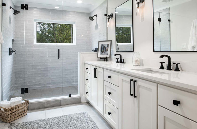 A white and black bathroom with a glass shower