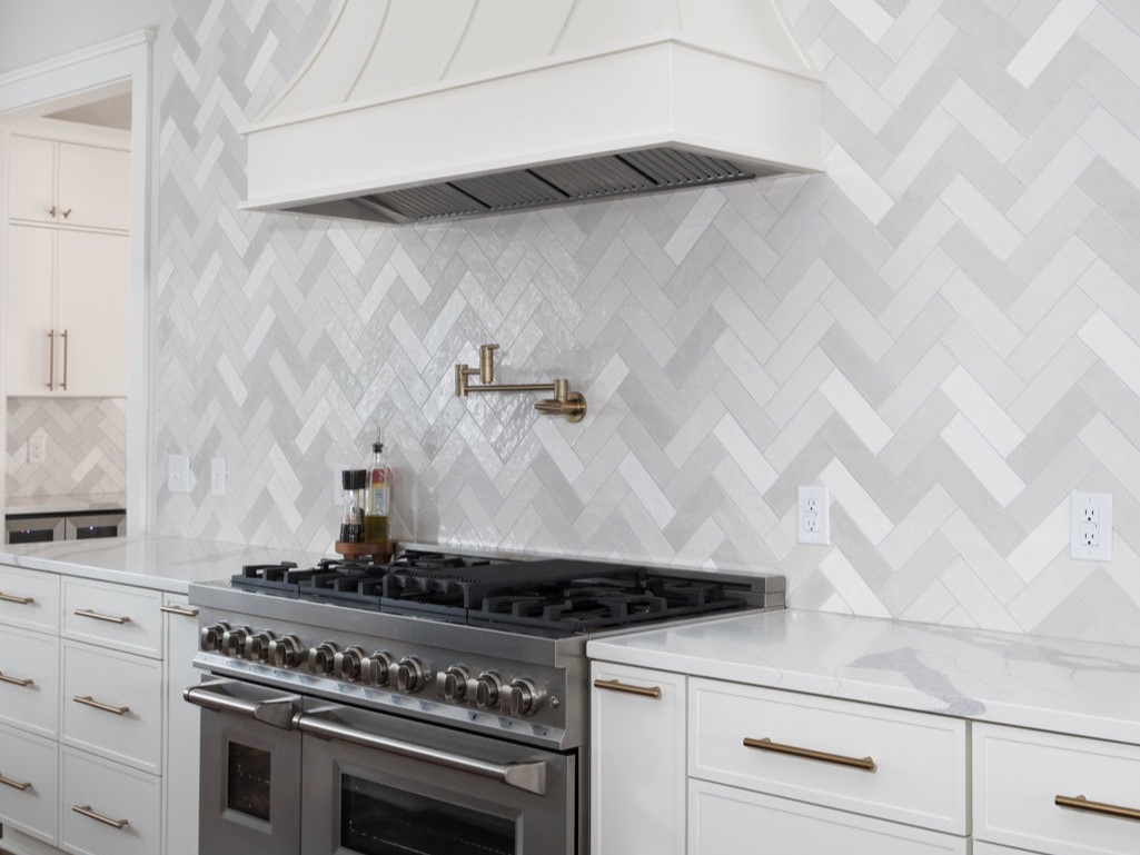 A white kitchen with a herringbone tile backsplash in Chantilly, Charlotte, NC
