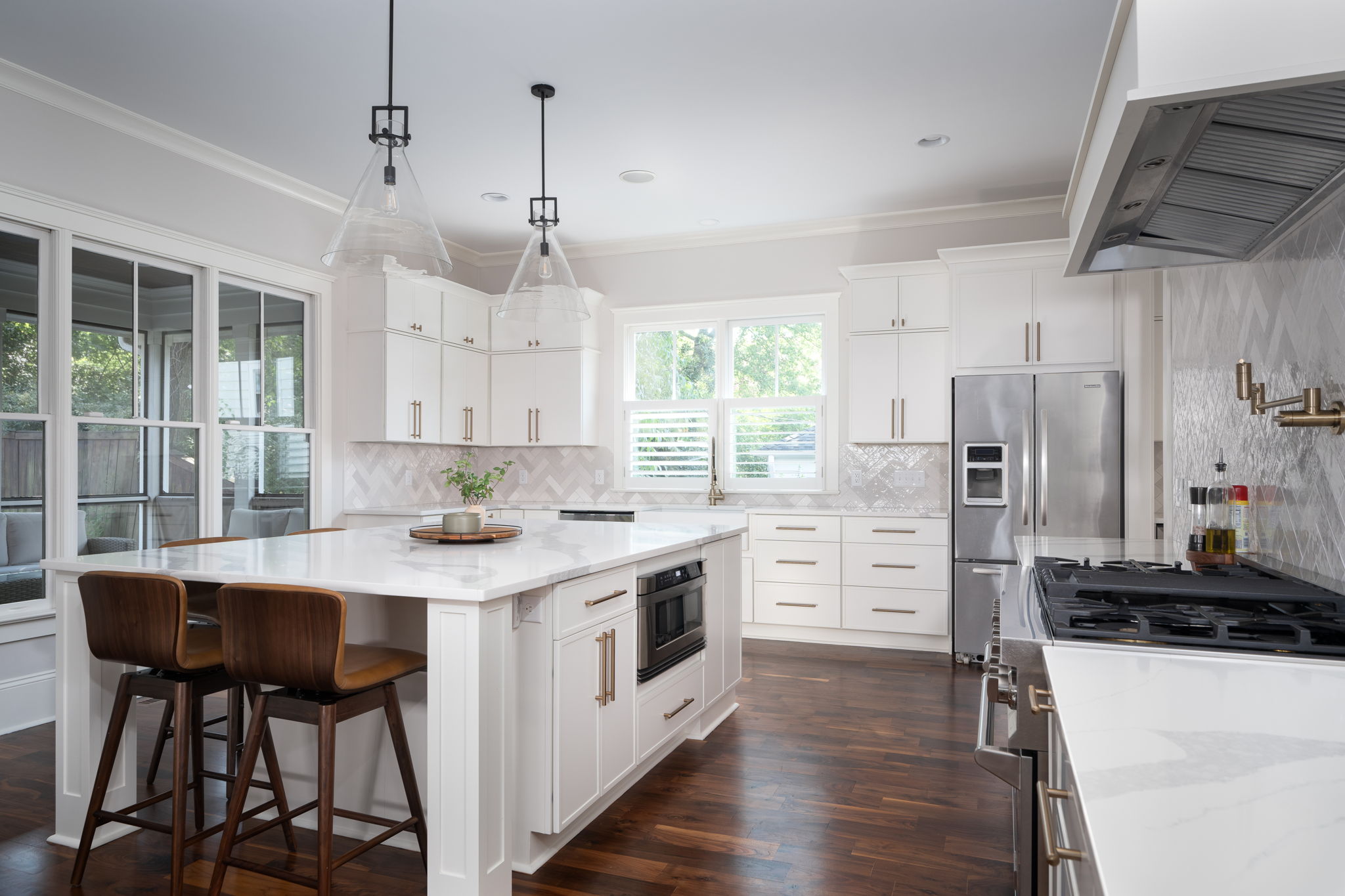 Modern kitchen with white cabinetry, stainless steel appliances, and a central island with bar stools, ideal for home renovations with the best return on investment, surrounded by hardwood floors and natural light.