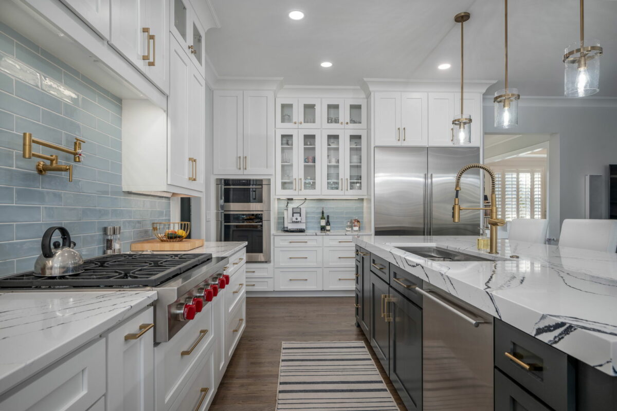 Modern kitchen with white cabinets, marble countertops, stainless steel appliances, and blue tile backsplash.