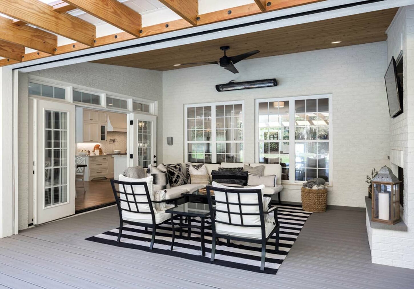 Modern patio area with black and white striped chairs, a sofa, coffee table, and an open view into a kitchen undergoing home remodeling in Charlotte.